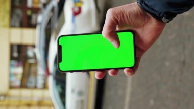 NEW YORK - 19 Aralık 2020: Şehir dışındaki bulanık internet krom üzerinde dikey yeşil ekran arka plan polis arabası kullanan dikey nişancı. Cep telefonu medya aygıtı. Yavaş çekim