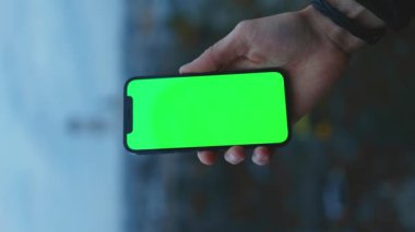 NEW YORK - 19 Aralık 2020: Eski kasabadaki bulanık arka plan görüntüsünde yeşil ekrandaki akıllı telefonu kullanan ve tıklayan bir adam görüntüsü bulanıklaştı. Dokunmatik ekran cep telefonu. Yavaş çekim