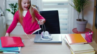 Genç kız koronavirüs salgını sırasında evde kulaklık kullanmaya başlıyor. Uzaktan eğitim kavramı. Gençlerin uzak interneti. Yavaş çekim