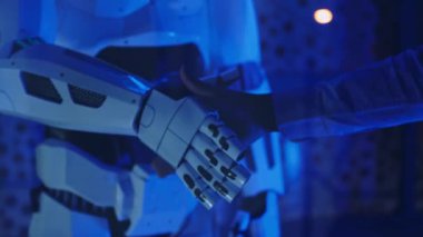 Sibernetik bir robotla tokalaşan bir iş adamının elini kapat. Yapay zekayla insan etkileşimi. Ortaklık, gelecek, üretkenlik, anlaşma, bilim. Yavaş çekim