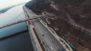 Helikopter manzaralı ve nehir kenarında arabaları olan bir yol. Drone, araba kamyonları, orman, turist, su, kentsel, altyapı, şehir, mimari, hava, seyahat. Yavaş çekim
