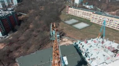 Emlak şirketinin inşaat sahasında uçan bir helikopter. Yüksek kule vinçleri ve kazıcılardaki insanlar inşaat binaları üzerinde çalışıyorlar..