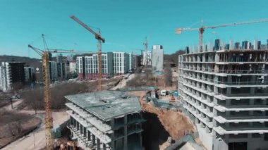 Meşgul mimarlar ve çok katlı apartmanlar inşa eden işçilerle birlikte emlak şantiyesinin üzerinden uçmak. Yeni inşaat gelişimi.