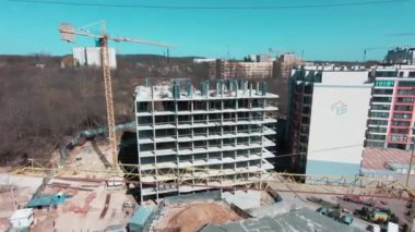 Yeni emlak şirketinin şantiyesinde helikopter uçuyor. Üniformalı insanlar inşaat kulesi vinçlerinde çalışıyorlar. Çok katlı apartmanlar inşa ediyorlar..