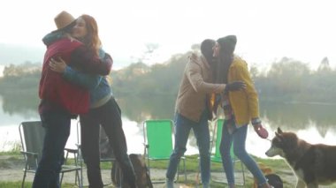 Arkadaşlar kamp ateşi üstüne göl kenarında sarılıyorlar. Beyaz kadın beyaz adamı kucaklıyor. Siyah adam grup kucaklaşmasına katılıyor, köpek sallıyor.