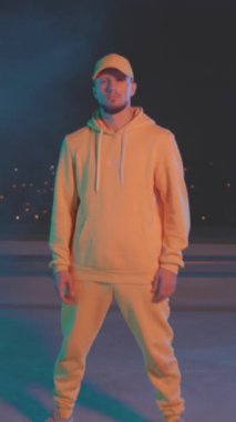 Gece yarısı çatıda poz veren sarı, beyaz erkek, pembe jöleli, kollarını kavuşturmuş gece portresi uzmanı.