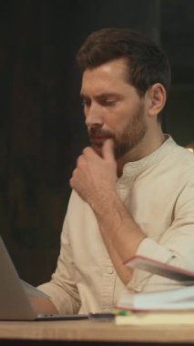 Adam dizüstü bilgisayar masasına odaklanmış, düşünceli serbest yazar analist ve tasarımcı rollerine geçiyor, fikirleri düşünmek için duraklıyor.,