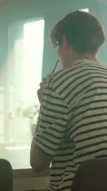 Genç beyaz adam akıllı telefon beslemesi, dilimlenmiş portakal suyu ve meyve suyu ile mutfak masası planlaması, konsantre ifade.,