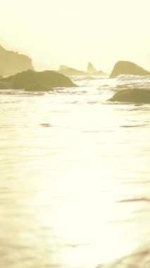 Köpüklü güneşli sahil sörfü, hareketli su ve uzak kaya yığınlarının parlak gölgeleri, enerjik köpüklü.