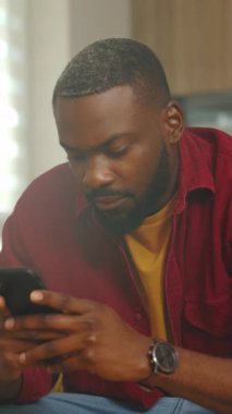 Siyah adam akıllı telefona odaklanmış, faturayı inceleyen serbest çalışan, öğrenci kontrol programı, alıcı fiyatları karşılaştıran, kapalı alan