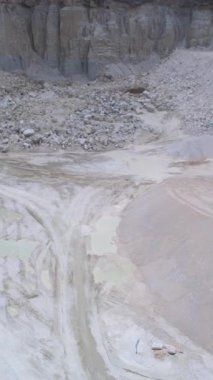 Taşıyıcı kamyonları olan hava ocağı zemini, geniş açık çukur panorama lastik izleri ve soluk su havuzları gösteren, damperli kamyonet.