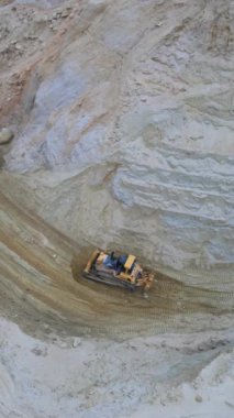 Buldozer kumlu taş ocağı yamaçlarını tarıyor, dozer takip ediyor büyük bıçağı gevşek kumda itiyor, kıvrımlı taşıma yolu oluşturuyor.