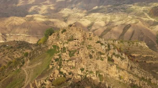 Verlaten in de bergen, het dorp Gamsutl. Onneembare vesting op een heuveltop. Ghost Town, ruïnes van een oude nederzetting. 4k uitzicht vanuit de lucht op een oud verlaten dorp in het Dagestan gebergte — Stockvideo