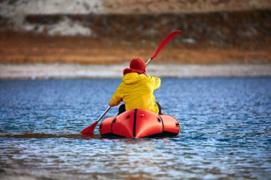 Sürünün içinde yüz. Packraft, tek kişilik hafif sal. Sefer ya da macera yarışı için kullanılan. Bir gölde, şişme bir teknede..