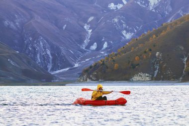 Sürünün içinde yüz. Packraft, tek kişilik hafif sal. Sefer ya da macera yarışı için kullanılan. Bir gölde, şişme bir teknede.