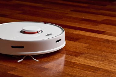 Ahşap zeminde akıllı robot elektrikli süpürge. Robot elektrikli süpürge daireyi belli bir zamanda otomatik olarak temizliyor. Akıllı ev
