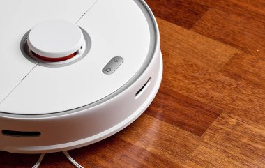 Ahşap zeminde akıllı robot elektrikli süpürge. Robot elektrikli süpürge daireyi belli bir zamanda otomatik olarak temizliyor. Akıllı ev
