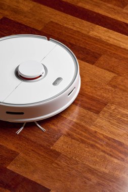 Ahşap zeminde akıllı robot elektrikli süpürge. Robot elektrikli süpürge daireyi belli bir zamanda otomatik olarak temizliyor. Akıllı ev