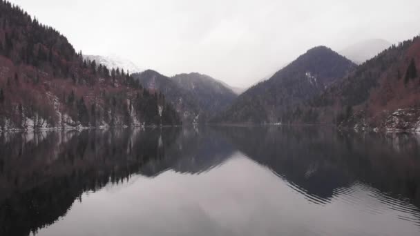 Vliegen over het wateroppervlak van een bergmeer. Meer en bergen, prachtige natuur. uitzicht op het meer in de winter, Uitzicht op de Drone — Stockvideo