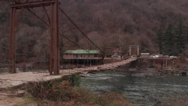 Vecchio ponte sospeso in legno su un fiume di montagna, vista dall'alto di un ponte abbandonato, d-cinelike, nessuna classificazione dei colori — Video Stock