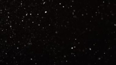 4K yavaş çekimde siyah zemin üzerinde gerçek kar yağışı. Besteleme için derecelendirilmemiş görüntüler, hareket grafikleri, büyük ve küçük kar taneleri, ıssız düşen kar taneleri