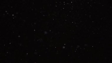 Güzel, düşen kar, siyah arka planda 4K yavaş çekimde izole edilmiş, 50 mm lensle çekilmiş. Besteleme için derecelendirilmemiş görüntüler, hareket grafikleri, büyük ve küçük kar taneleri, ıssız düşen kar taneleri