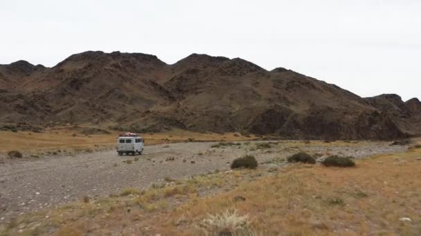 Off-road vehicle goes on a dirt road among the mountains. Beautiful wild road in the mountains. Mountain landscape in the wild, Road trip through a desert Aerial View — Stock Video