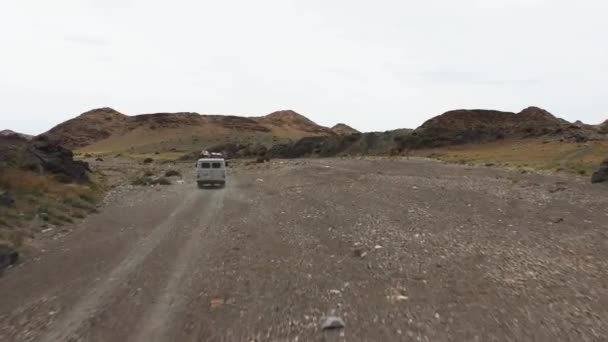 Off-road vehicle goes on a dirt road among the mountains. Beautiful wild road in the mountains. Mountain landscape in the wild, Road trip through a desert Aerial View — 图库视频影像