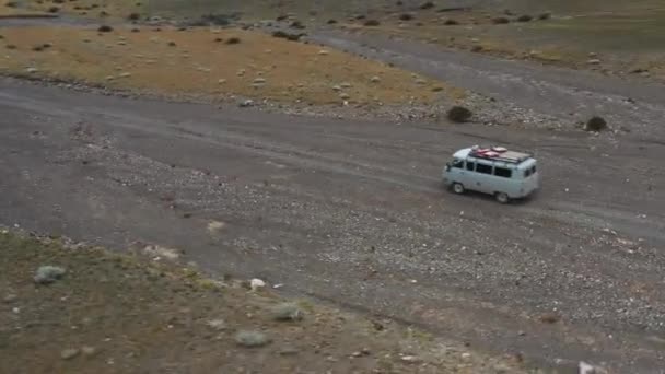 Véhicule tout-terrain va sur un chemin de terre parmi les montagnes. belle route sauvage dans les montagnes. paysage montagneux dans la nature, road trip à travers un désert vue aérienne — Video