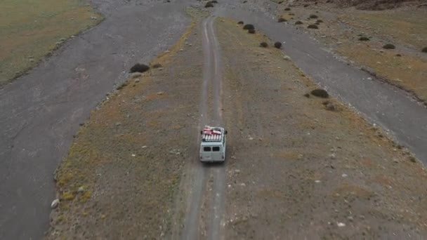 Off-road vehicle goes on a dirt road among the mountains. Beautiful wild road in the mountains. Mountain landscape in the wild, Road trip through a desert Aerial View — Vídeo de Stock