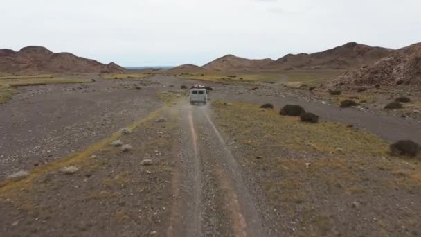 Off-road vehicle goes on a dirt road among the mountains. Beautiful wild road in the mountains. Mountain landscape in the wild, Road trip through a desert Aerial View — Stok video