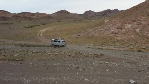 Off-road vehicle goes on a dirt road among the mountains. Beautiful wild road in the mountains. Mountain landscape in the wild, Road trip through a desert Aerial View — 图库视频影像