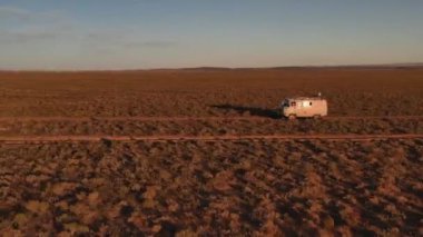 Çölün ortasında toprak yol boyunca giden 4x4 numaralı hava manzaralı araba. Gün batımında çölde güzel vahşi bir yol. Çöl manzaralı bir yolculukta
