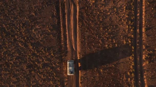 Luftaufnahme eines Geländewagens, der auf einer unbefestigten Straße durch die Wüste fährt. Schöne wilde Straße in der Wüste bei Sonnenuntergang. Roadtrip durch die Wüste aus der Luft — Stockvideo