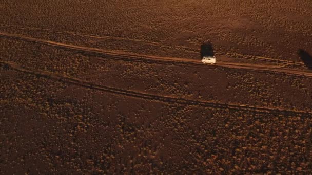 Aerial view off road 4x4 car driving along dirt road among the desert. Beautiful wild road in the desert at sunset. Road trip through a desert Aerial View — Stock Video