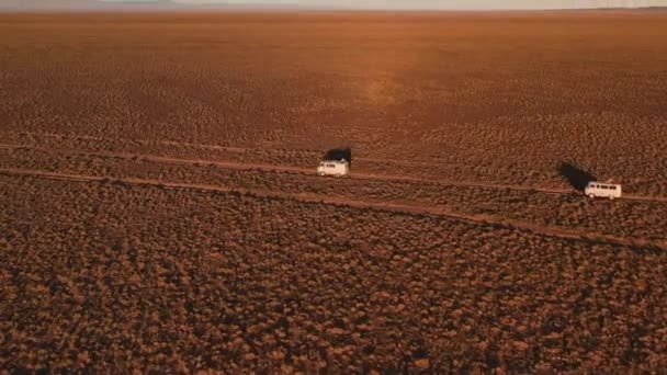 Widok z lotu ptaka off road 4x4 samochód jazdy po polnej drodze wśród pustyni. Piękna dzika droga na pustyni o zachodzie słońca. Wycieczka przez pustynię Widok z lotu ptaka — Wideo stockowe