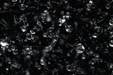 Sıvının yüzeyine su sıçrıyor ve düşüyor. Soyut Siyah Arkaplan Sıvı Doku