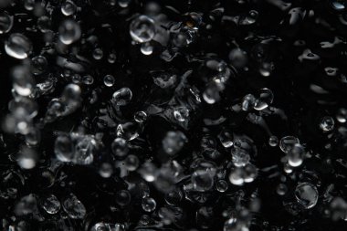 Sıvının yüzeyine su sıçrıyor ve düşüyor. Soyut Siyah Arkaplan Sıvı Doku