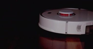 Ahşap zemininde karaciğer olan akıllı robot süpürgesi. Robot elektrikli süpürge daireyi otomatik olarak temizliyor. 4K ağır çekim 100 fps, ProRes 422, 10 bit.