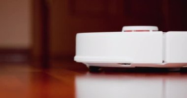 Ahşap zemininde karaciğer olan akıllı robot süpürgesi. Robot elektrikli süpürge daireyi otomatik olarak temizliyor. 4K ağır çekim 100 fps, ProRes 422, 10 bit.