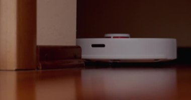 Ahşap zemininde karaciğer olan akıllı robot süpürgesi. Robot elektrikli süpürge daireyi otomatik olarak temizliyor. 4K ağır çekim 100 fps, ProRes 422, 10 bit.