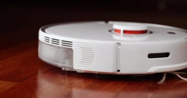 Ahşap zemininde karaciğer olan akıllı robot süpürgesi. Robot elektrikli süpürge daireyi otomatik olarak temizliyor. 4K ağır çekim 100 fps, ProRes 422, 10 bit.