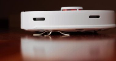 Ahşap zemininde karaciğer olan akıllı robot süpürgesi. Robot elektrikli süpürge daireyi otomatik olarak temizliyor. 4K ağır çekim 100 fps, ProRes 422, 10 bit.