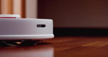 Ahşap zemininde karaciğer olan akıllı robot süpürgesi. Robot elektrikli süpürge daireyi otomatik olarak temizliyor. 4K ağır çekim 100 fps, ProRes 422, 10 bit.