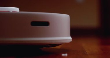 Ahşap zemininde karaciğer olan akıllı robot süpürgesi. Robot elektrikli süpürge daireyi otomatik olarak temizliyor. 4K ağır çekim 100 fps, ProRes 422, 10 bit.