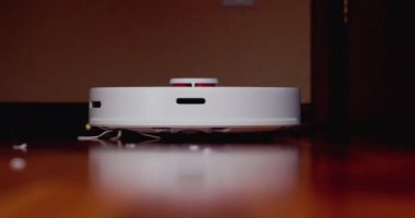 Ahşap zemininde karaciğer olan akıllı robot süpürgesi. Robot elektrikli süpürge daireyi otomatik olarak temizliyor. 4K ağır çekim 100 fps, ProRes 422, 10 bit.