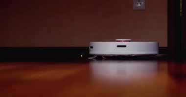 Ahşap zemininde karaciğer olan akıllı robot süpürgesi. Robot elektrikli süpürge daireyi otomatik olarak temizliyor. 4K ağır çekim 100 fps, ProRes 422, 10 bit.