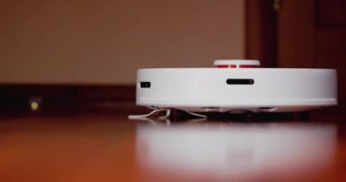 Ahşap zemininde karaciğer olan akıllı robot süpürgesi. Robot elektrikli süpürge daireyi otomatik olarak temizliyor. 4K ağır çekim 100 fps, ProRes 422, 10 bit.