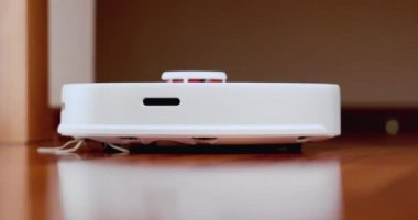 Ahşap zemininde karaciğer olan akıllı robot süpürgesi. Robot elektrikli süpürge daireyi otomatik olarak temizliyor. 4K ağır çekim 100 fps, ProRes 422, 10 bit.