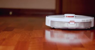 Ahşap zemininde karaciğer olan akıllı robot süpürgesi. Robot elektrikli süpürge daireyi otomatik olarak temizliyor. 4K ağır çekim 100 fps, ProRes 422, 10 bit.